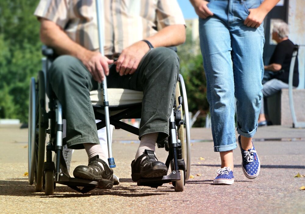 Een afbeelding van een zorgbehoevende man in een rolstoel een een zzp'er in de zorg, 